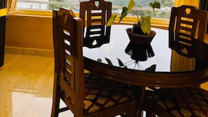 Un coin repas avec une table et des chaises, une fenêtre avec des rideaux et une vue sur un paysage montagneux.