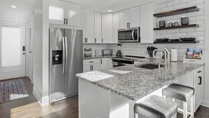 A modern kitchen with white cabinets, stainless steel appliances, a granite countertop, and bar stools. - 2-bedroom condo in Keowee Key: 3 pools, 2 restaurants, fitness center, golf (Salem)