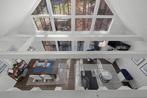 Ein mehrgeschossiges Interieur mit Essbereich, Sitzgelegenheiten und Blick ins Freie durch große Fenster.