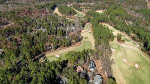 An aerial view of a golf course with a clubhouse, surrounded by dense forest and distant mountains. - 2-bedroom condo in Keowee Key: 3 pools, 2 restaurants, fitness center, golf (Salem)