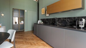 A modern kitchen with a marble countertop, grey cabinets, and a wooden herringbone floor. - Brera Apartments in Gae Aulenti (Milan)