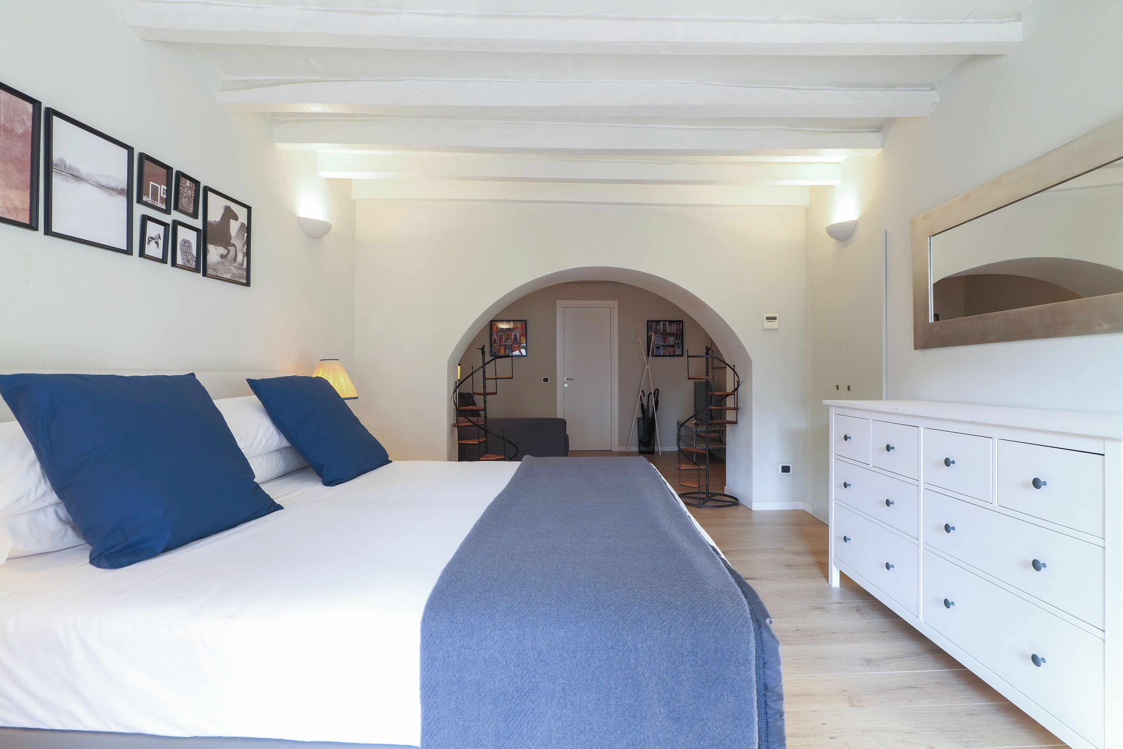 Un dormitorio con cama, cómoda y un pasillo que lleva a otra habitación.