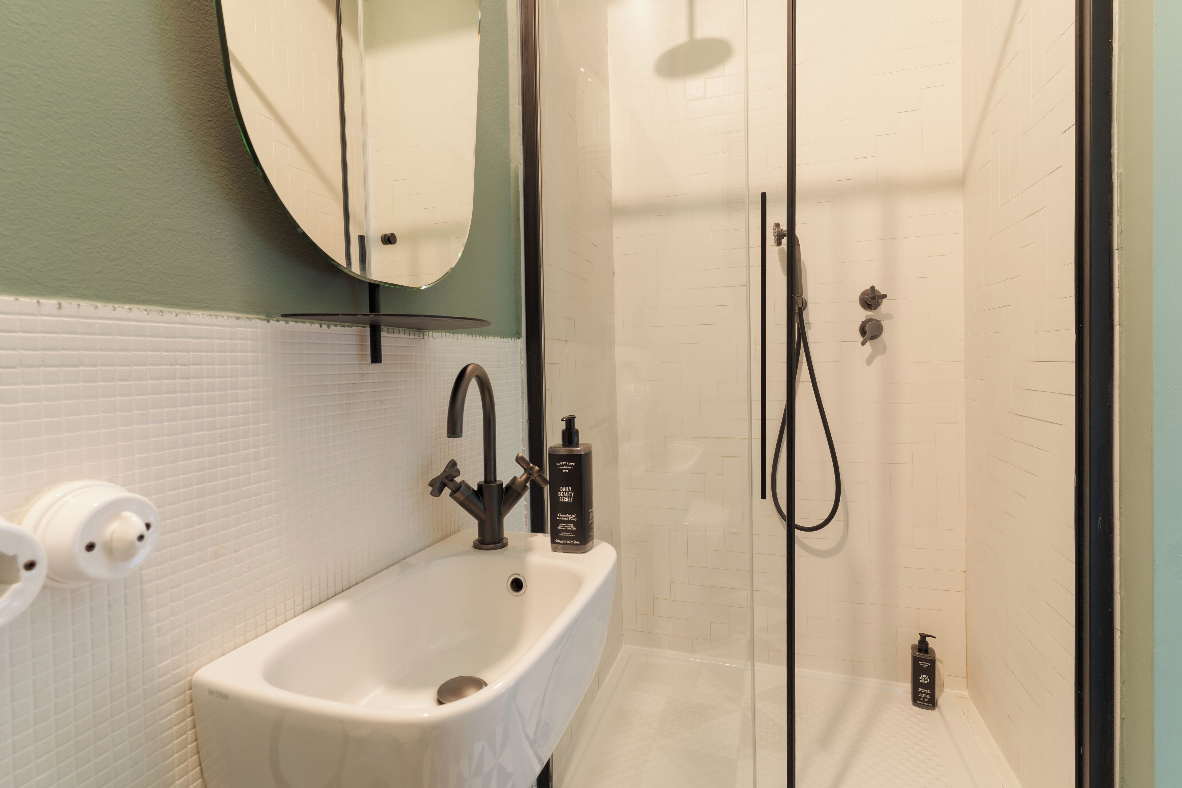 Une salle de bain avec un lavabo blanc, un miroir et un espace douche.