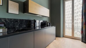 A modern kitchen with a dark countertop, a built-in oven, and a window with a view of a balcony. - Brera Apartments in Gae Aulenti (Milan)