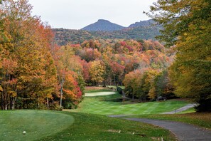 A golf course with a pond, surrounded by autumn-colored trees and a mountain in the background. - Reserve 32B • Family-Friendly Mountain Stay (Sugar Mountain)
