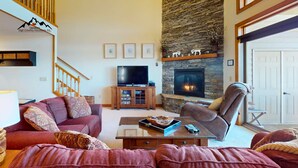 A living room with a stone fireplace, a television, and a comfortable seating area. - Reserve 32B • Family-Friendly Mountain Stay (Sugar Mountain)