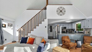 A modern living room with a staircase, a kitchen, and a dining area. - Dog-Friendly Chalet in The Woods Resort w/ Fire Pit (Hedgesville)