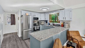 A modern kitchen with white cabinetry, granite countertops, stainless steel appliances, and a large island. - Dog-Friendly Chalet in The Woods Resort w/ Fire Pit (Hedgesville)
