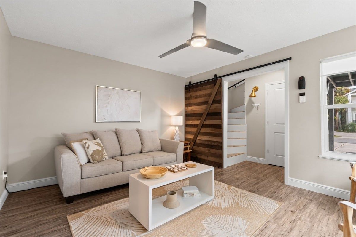 Un salon avec un canapé, une table basse et un ventilateur de plafond.