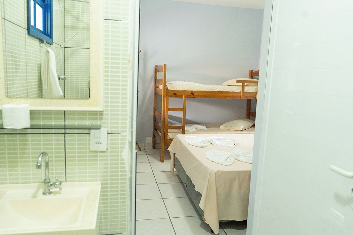 A small, clean room with a bunk bed, a sink, and a mirror.
