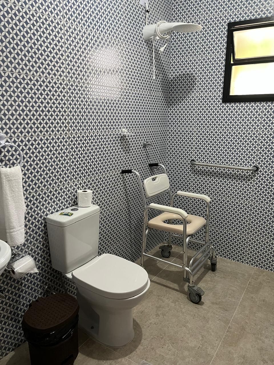 Casa de banho moderna com parede estampada, sanita, bidé, secador de mãos e porta-toalhas.