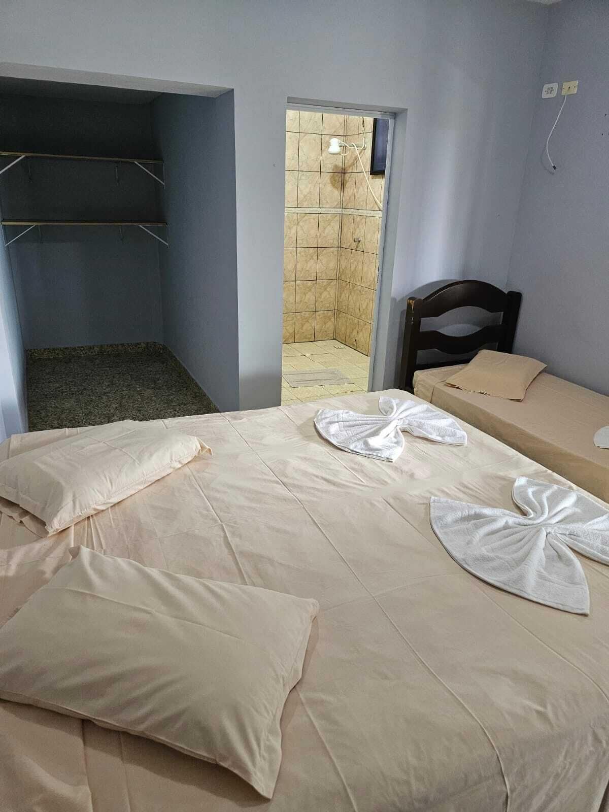 Una habitación con cama, una silla de madera, una mesita, un armario y zona de ducha.