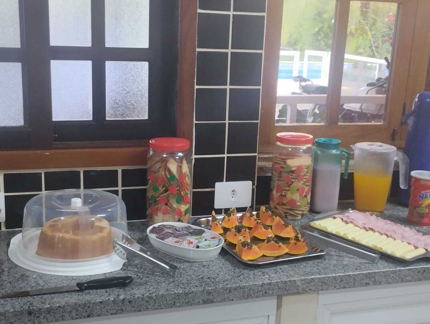 A kitchen counter with food items, a cake, and a window with a view of a vehicle outside.