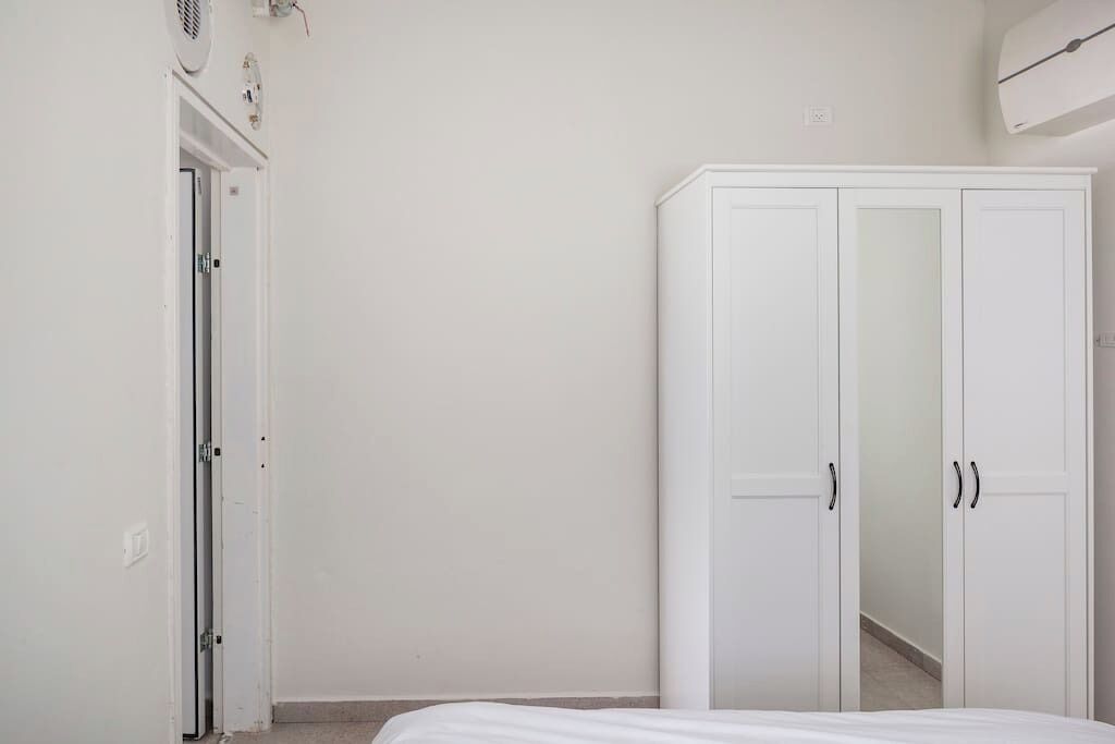 A bedroom with a bed, a wardrobe, and a door.