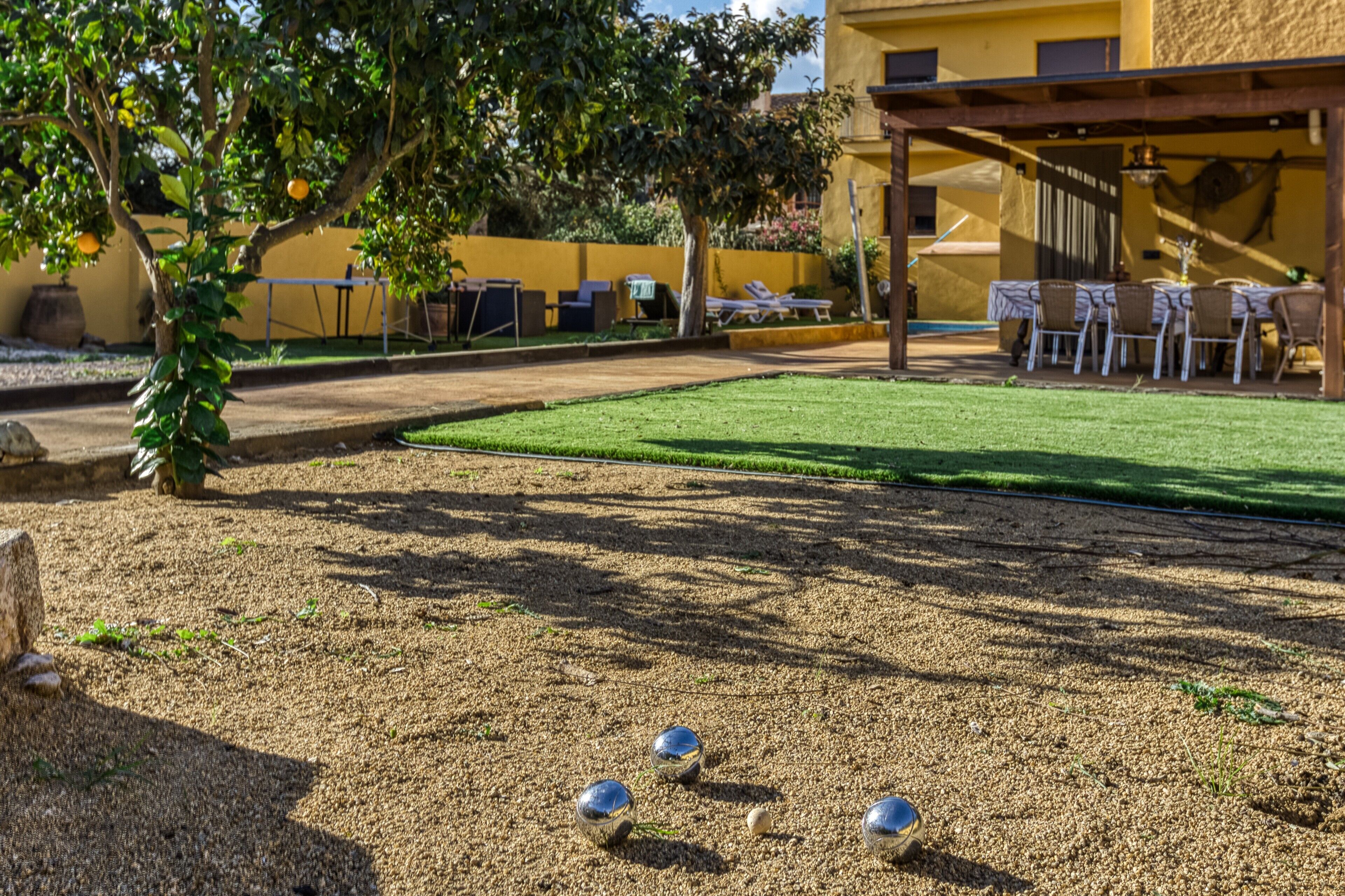 Un patio con césped, una pérgola y mobiliario de exterior.