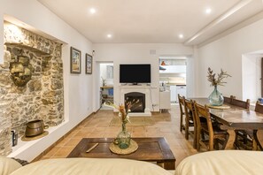 Un salon avec un mur en pierre, une cheminée, une table à manger et des chaises.