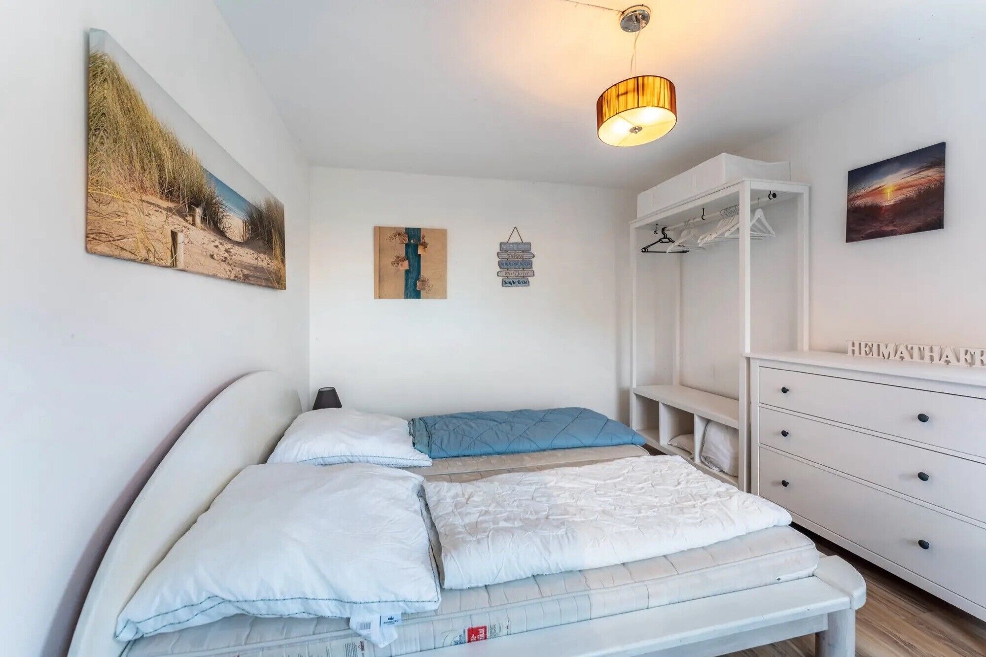 Une chambre à coucher comprenant un lit, une armoire, un bureau et un luminaire suspendu.