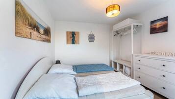 Une chambre à coucher comprenant un lit, une armoire, un bureau et un luminaire suspendu.