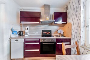 Una cocina compacta con horno integrado, cafetera y microondas.