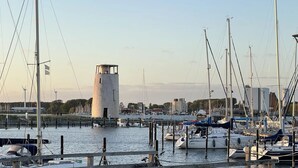 Uma marina com barcos atracados, um farol e um píer de madeira.