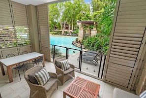 A balcony with a pool, wicker furniture, and a view of a tropical garden. - Sensational Swim Out—Resort Living by the Sea (Palm Cove)