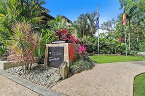 Skilt for Pullman Palm Cove Sea Temple Resort & Spa, med grussti og tropiske planter.