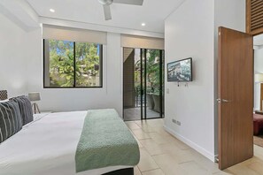 A modern bedroom with a large bed, a television, and a sliding door leading to a balcony. - Orchid at Temple Resort: A Swim-out Tropical Oasis (Palm Cove)