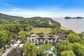 A resort with multiple buildings, a swimming pool, and a beach view. - Orchid at Temple Resort: A Swim-out Tropical Oasis (Palm Cove)