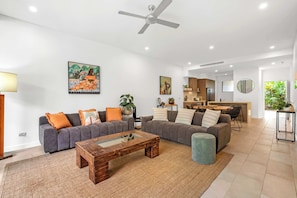 A modern living room with a grey sofa set, a wooden coffee table, and a ceiling fan. - Sensational Swim Out—Resort Living by the Sea (Palm Cove)