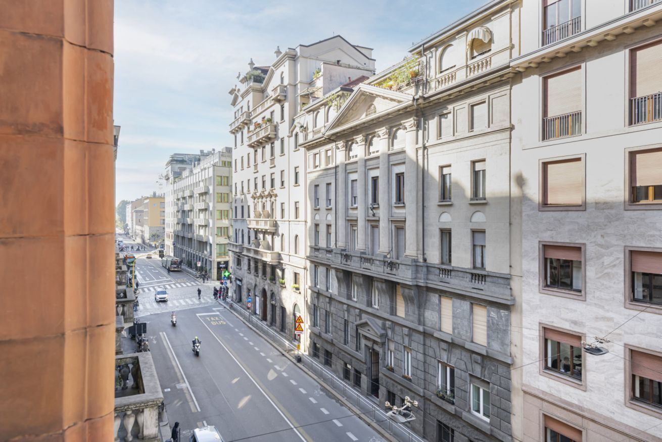 A street view of a city with multi-story buildings, a clear road, and a pedestrian crossing.