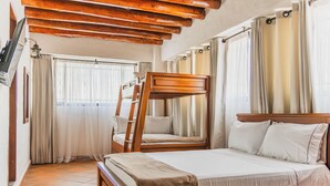 A bedroom with a bunk bed, a wooden headboard, a large bed with white linens, and a window with curtains. - Hotel Prados de la Serranía (Lebrija)
