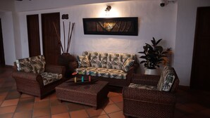 A living room with a sofa, two armchairs, a coffee table, and a potted plant. - Hotel Prados de la Serranía (Lebrija)