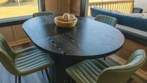 Een ronde tafel met een donkere, getextureerde blad, omringd door vier groene fauteuils. Op de tafel staat een houten schaal met eieren.
