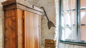 Una stanza rustica con un armadio di legno, una pala e una finestra con tende.