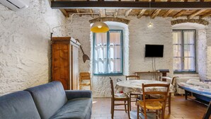 Una stanza rustica con un divano, un tavolo da pranzo in legno, sedie, una televisione e un letto.