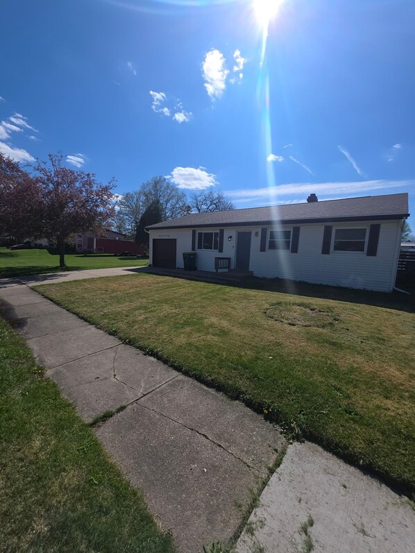 A single-story house with a front yard, a driveway, and a clear sky.