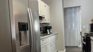 A modern kitchen with stainless steel appliances, white cabinetry, and a wooden floor. - Beautifully renovated spacious home in Mishawaka (Mishawaka)