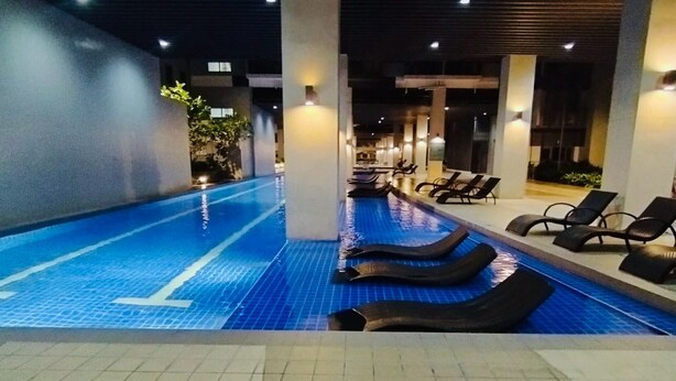 A swimming pool with lounge chairs and a tiled floor. - S Residences MOA by darpm (Pasay)