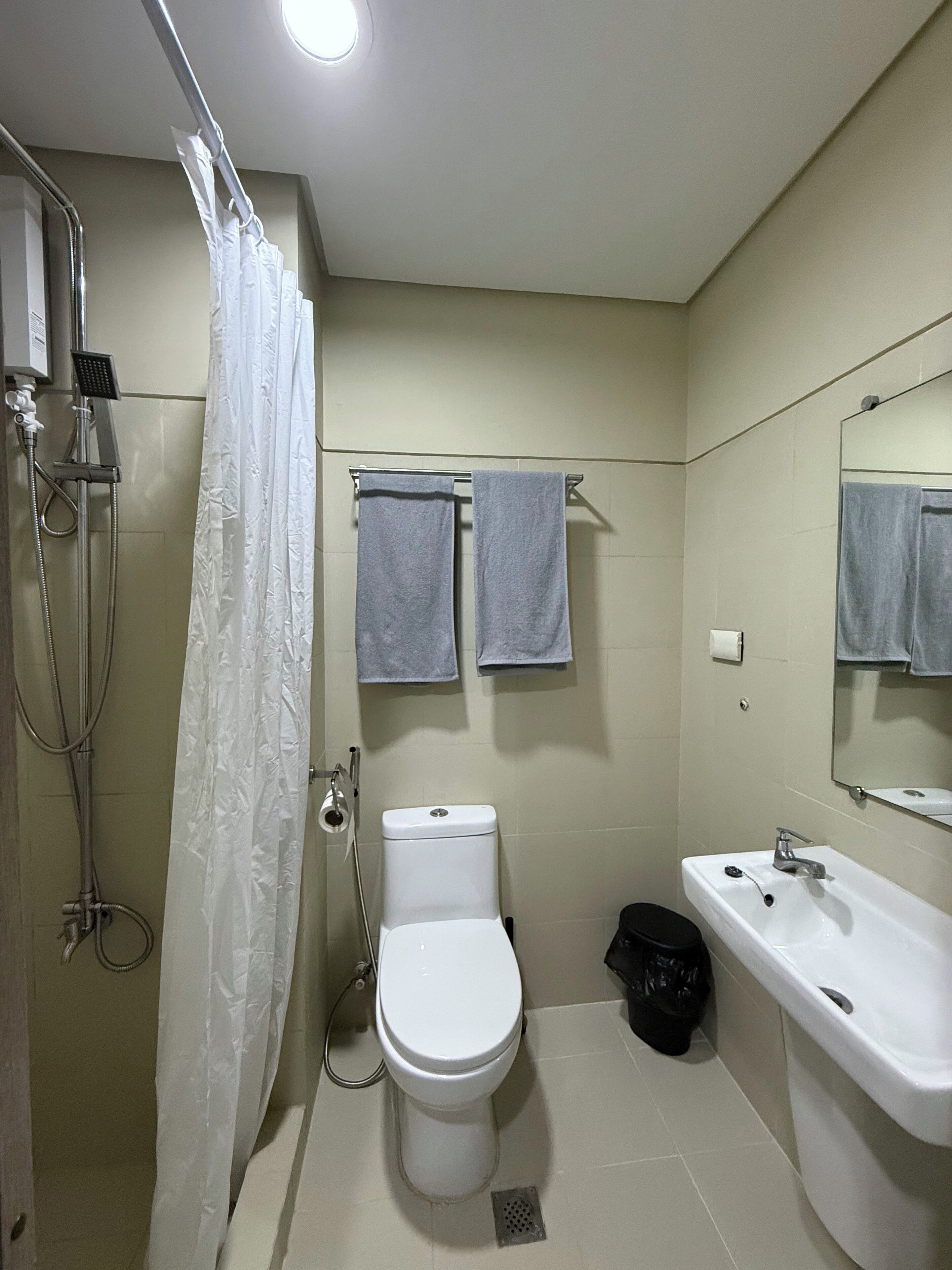 A bathroom with a shower, toilet, sink, and towel rack.