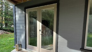 Une terrasse en bois avec une porte vitrée donnant sur un porche abrité.