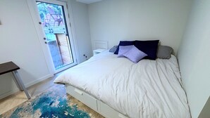Une chambre à coucher comprenant un lit, un bureau et une porte donnant sur un espace extérieur.