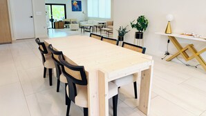 Un comedor amplio con una larga mesa de madera, sillas negras y una pared blanca con un cuadro.