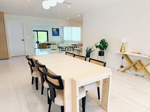 Ein geräumiger Essbereich mit einem langen Holztisch, schwarzen Stühlen und einer weißen Wand mit einem Gemälde.