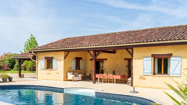 Una casa con piscina, terraza techada y comedor.