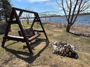 Un columpio de madera y una pila de leña junto a un lago.