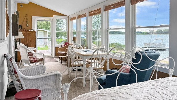 Une pièce avec vue sur un lac, des meubles en osier et une table avec des chaises.