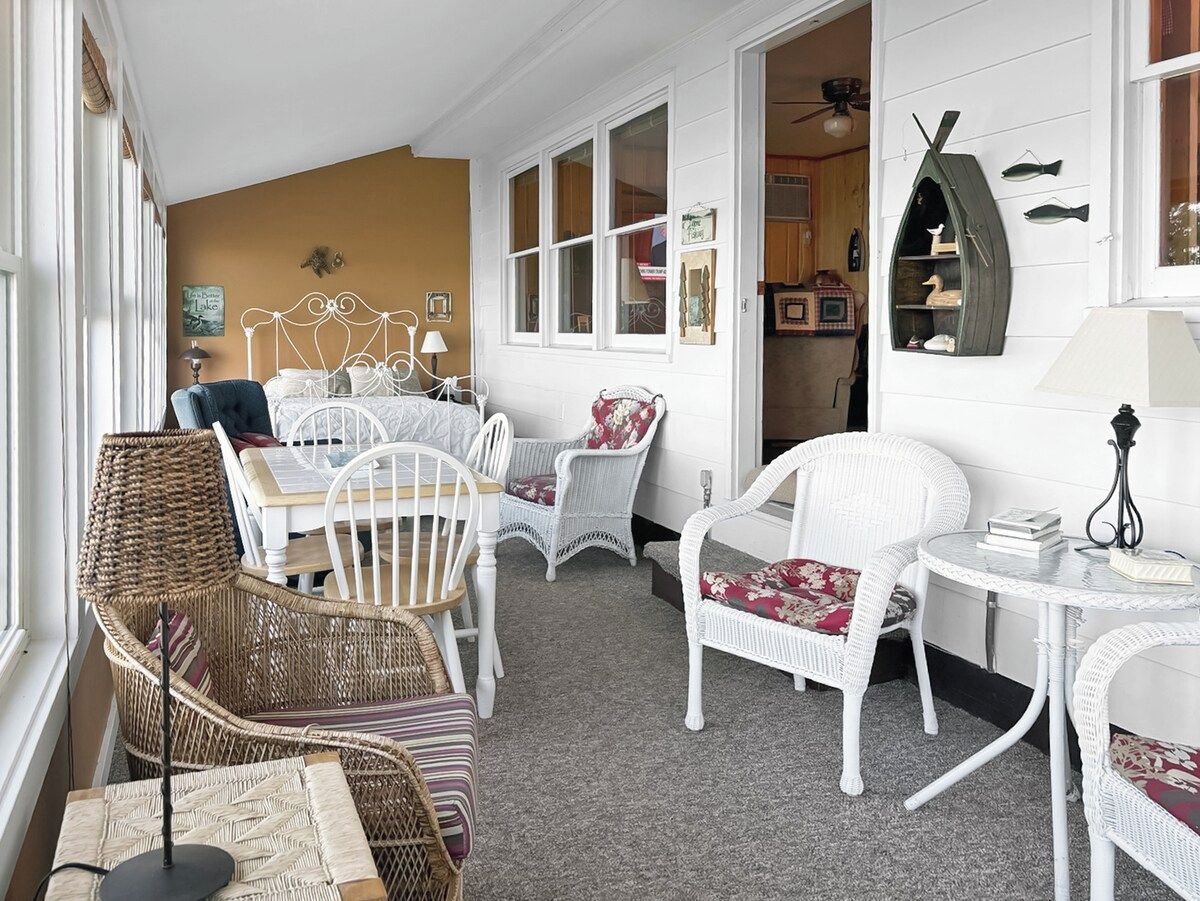 Une pièce chaleureuse, meublée de meubles en osier, avec une table blanche et une étagère décorative en forme de poisson.