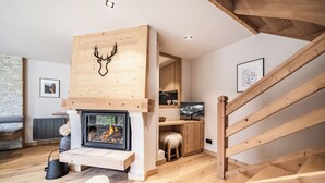 A modern living room with a fireplace, wooden beams, and a cozy seating area. - Snowdust – Warm & Welcoming Stay in Megève (Megeve)