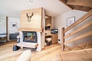 A modern living room with a fireplace, wooden beams, and a cozy seating area. - Snowdust – Warm & Welcoming Stay in Megève (Megeve)