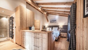 A bedroom with a wooden ceiling, a bed, a bedside table, and a nightstand. - Snowdust – Warm & Welcoming Stay in Megève (Megeve)
